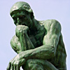 Photo of Rodin's "The Thinker," a statue of a seated man, chin resting on hand and deep in thought.