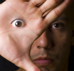 A digitally altered photograph in which a man has an eye on his hand.