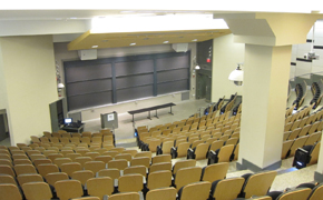 A large lecture hall with tiered seating and nine chalkboards.