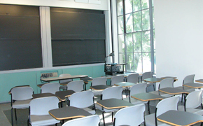 A small classroom with armchairs, as well as projectors and chalkboards at the front of the class.