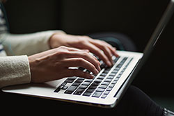 A woman's hands typing on a laptop computer.