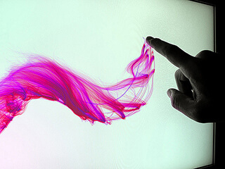 A person's finger creates a pink wave-like image on a touchscreen.