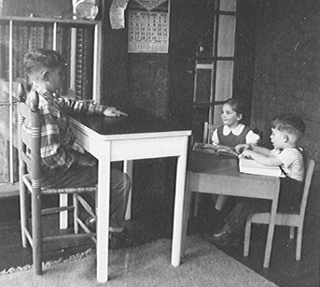 Black and white photograph of young children at desks.
