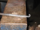 A tapered bar with two right-angle bends roughly an inch apart, forming a hook that could be hung over a door, for example.