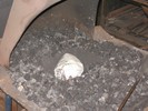 A rolled ball of newspaper 8" wide, in a rectangular depression in the forge, surrounded by coal that's been shoveled out of the way.