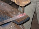 The workpiece and punch are moved to the corner of the anvil, over the pritchel hole.