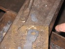 Photo of the cut off metal, the bronze plate, and the bottle opener, which shows the hole is now relatively centered in the end of the bar.