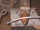 The red-hot section 6-inch from the end of the bar is curved over the anvil horn.
