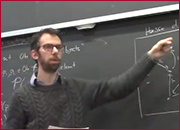 A men standing in front of a blackboard and pointing the blackboard with left hand.