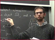A men standing in front of a blackboard and pointing the blackboard with right hand.
