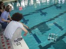 One student uses a control pad to drive the robot around the pool.