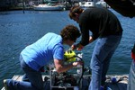 On the dock, two people work on the ROV.