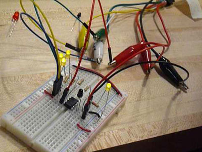 Photo of circuit built in a breadboard, with many wires and clips coming out of it.
