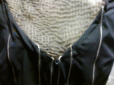 Photo of the front neckline portion of the dress, constructed of a light-colored (sheer?) material with thin wires embedded in it. 