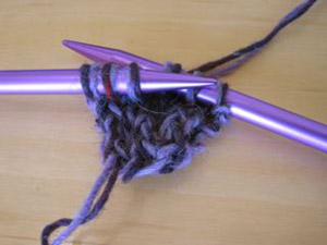Photo of a bit of knitted yarn on the ends of two knitting needles.