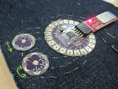 Close-up photo of several electronic devices sewn into a piece of fabric.