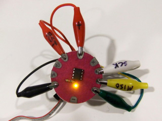 Photo of a fabric circuit with ATiny13 in the center, and several alligator clips attached to the fabric circuit.