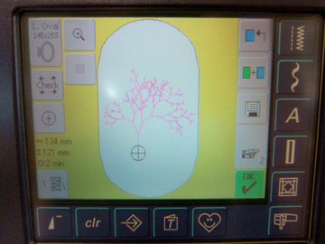 Photo of embroidery pattern on a small electronic display, surrounded by control buttons.