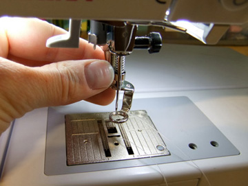 Photo showing hand attaching a presser foot on a sewing machine.