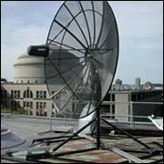 A big parabolic dish antenna in front of a building.