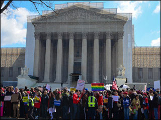 A group of demonstrators stands in front of the U.S. Supreme Court Building.