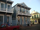 An intact two story blue building with a white porch.