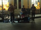 Four musicians stand in the street playing music.
