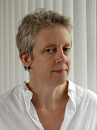 A headshot of a white woman with grey hair in a white collared shirt.