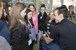 Several girls are standing around a man, asking him questions.