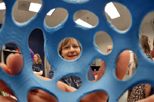 A woman holds a 3D printed object up to the camera.
